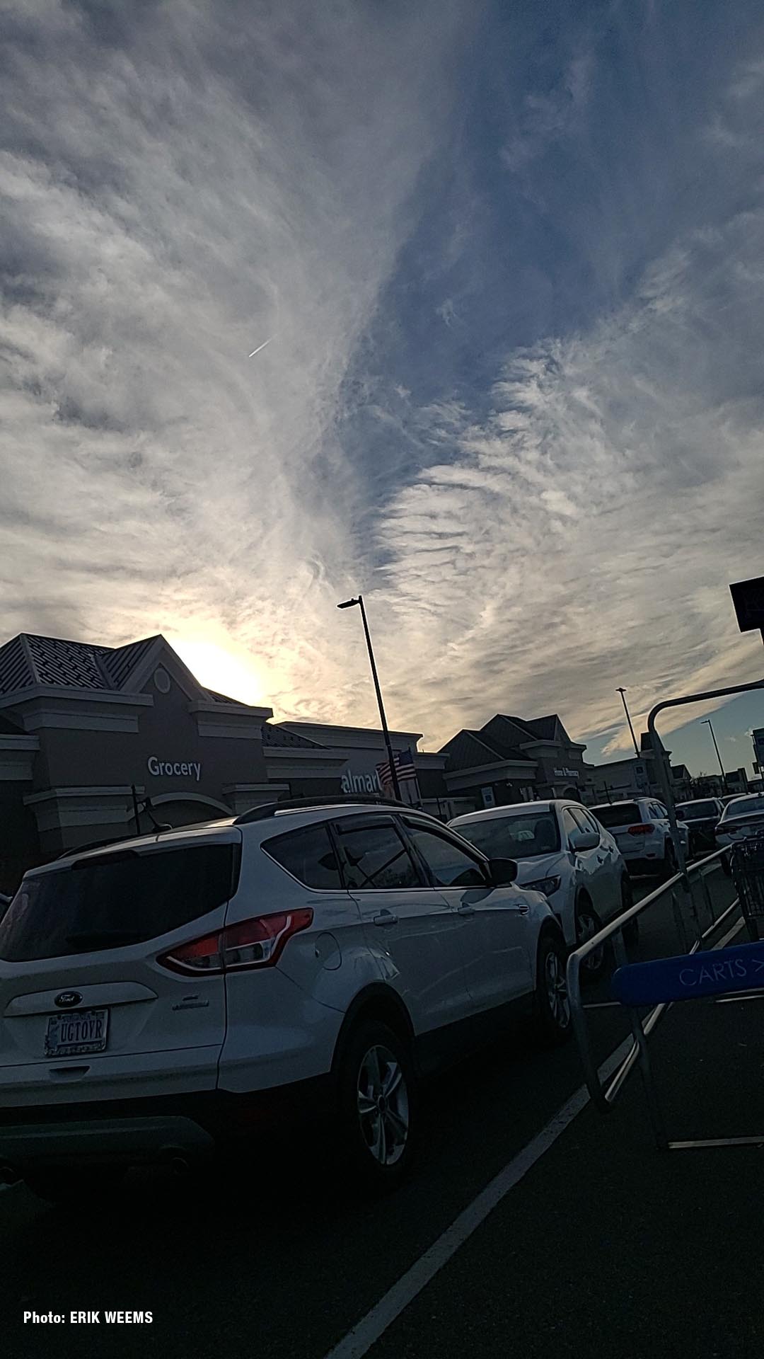 White streak in a winters sky over parking lot of grocery